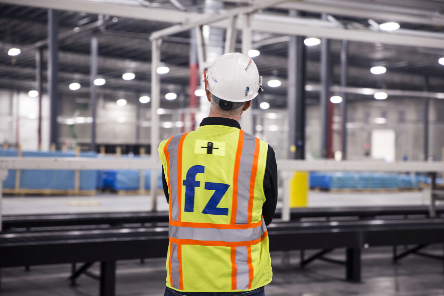 electrician with his back to the camera, looking out at facility